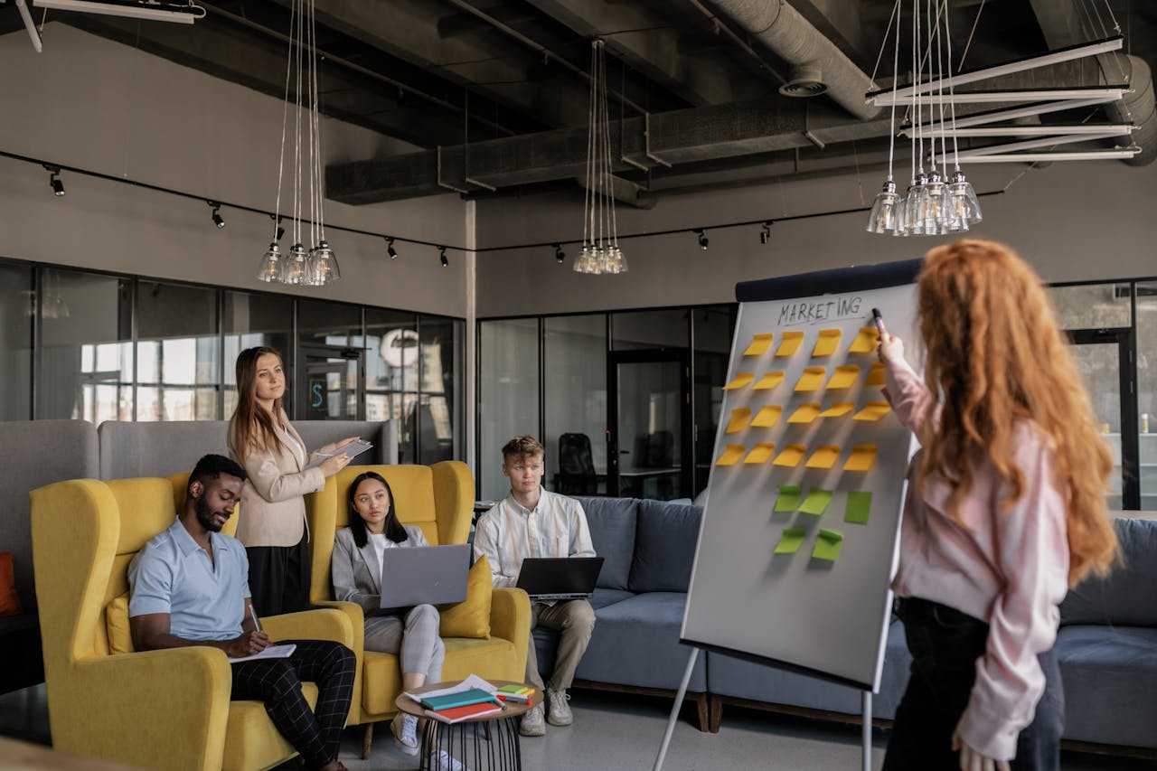 Photo of a Woman Pointing at a Whiteboard with Sticky Notes